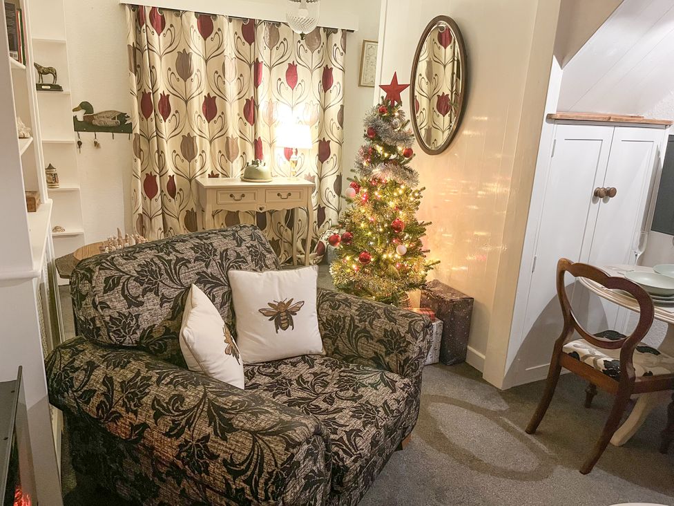 A living room with a Christmas tree and sofa at Bumble Bee at 2 Clematis Cottage near Clee Hill