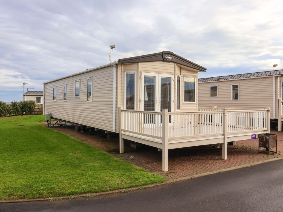 A mobile home with a deck and grass area at The Drift near High Skirlington near Skipsea