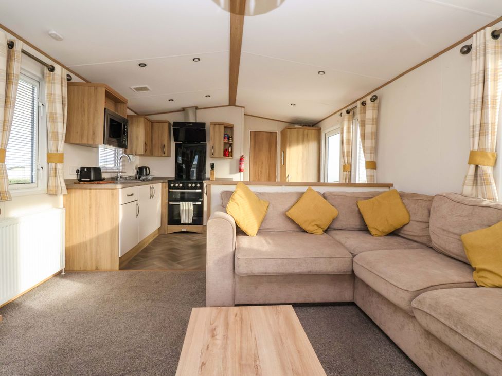 A living room with a sofa and kitchen area at The Drift High Skirlington near Skipsea
