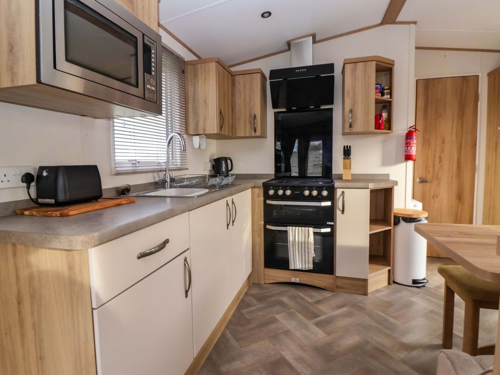 A kitchen with a microwave, sink, and cooker at The Drift in High Skirlington near Skipsea