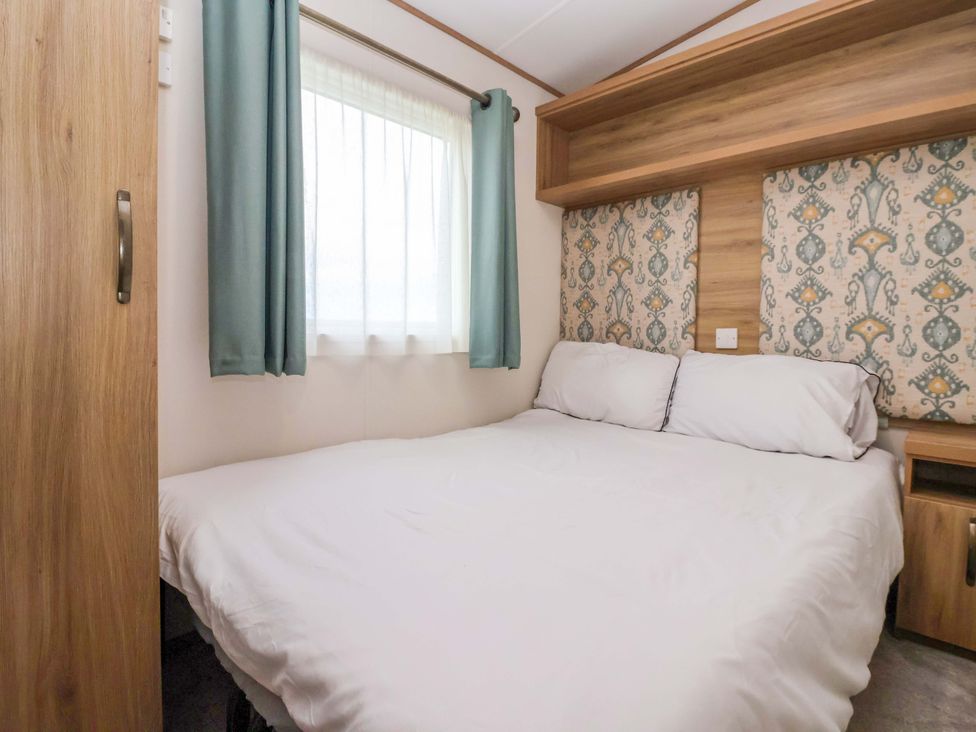 A bedroom with a bed and curtains at The Drift near Skipsea