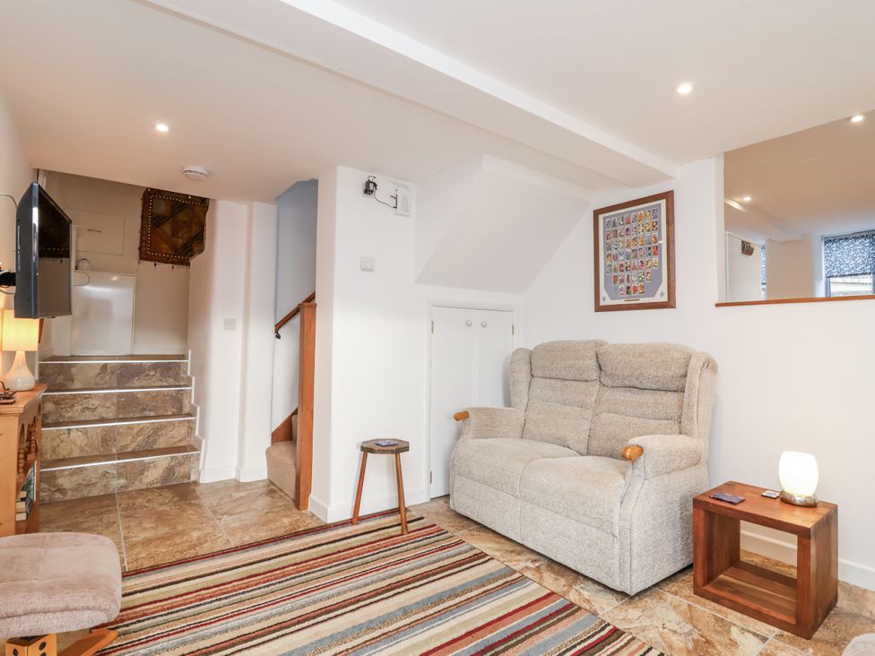 A living room with a sofa and a television at Dairy Cottage in Bullhornstone near South Brent