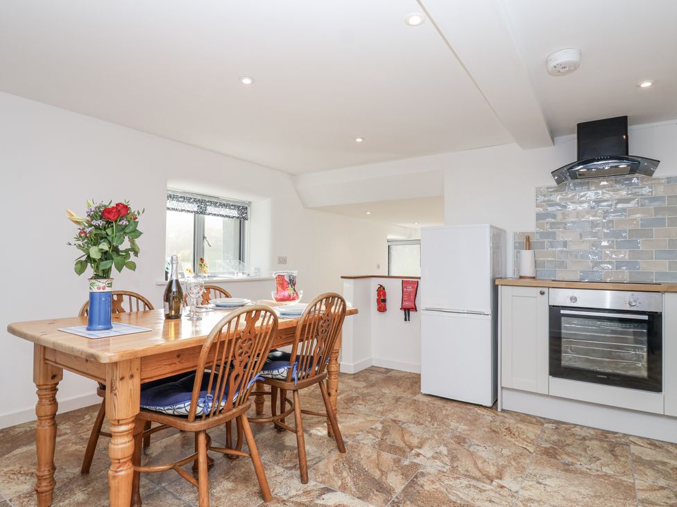 A kitchen with a dining table and chairs at Dairy Cottage in Bullhornstone near South Brent
