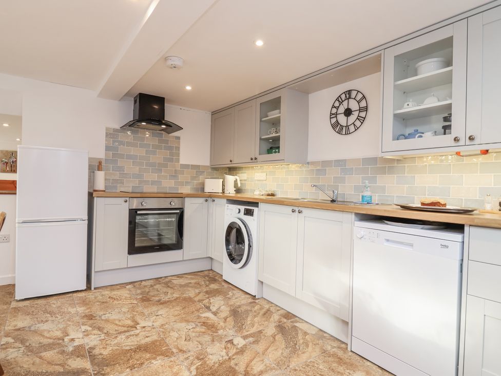 A kitchen with a refrigerator, oven, washing machine, and dishwasher at Dairy Cottage in Bullhornstone near South Brent