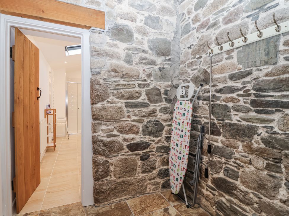A utility room with an ironing board and hooks at Dairy Cottage Bullhornstone near South Brent