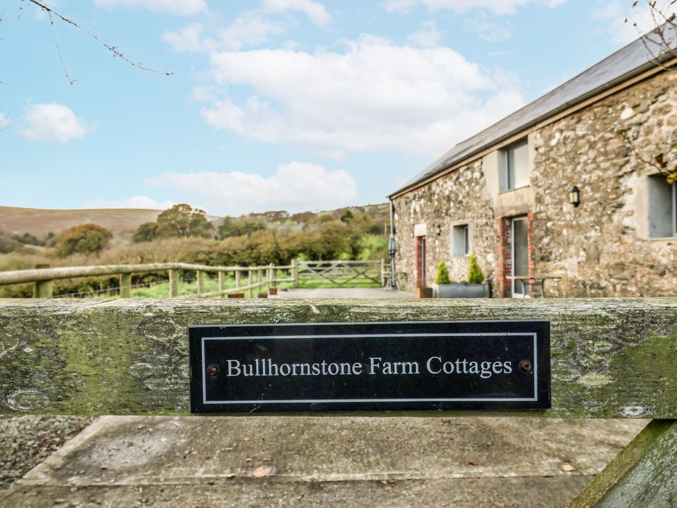 Sign for Bullhornstone Farm Cottages with cottages and hills in the background at Dairy Cottage Bullhornstone near South Brent