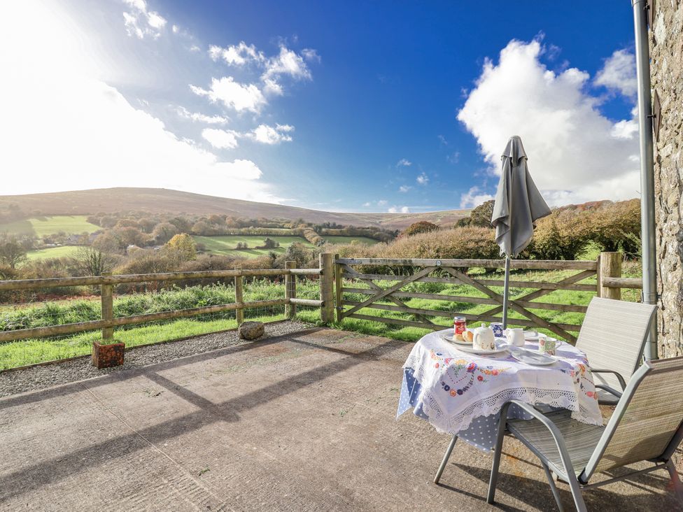 An outdoor patio with a table and chairs at Swallow Cottage Bullhornstone near South Brent