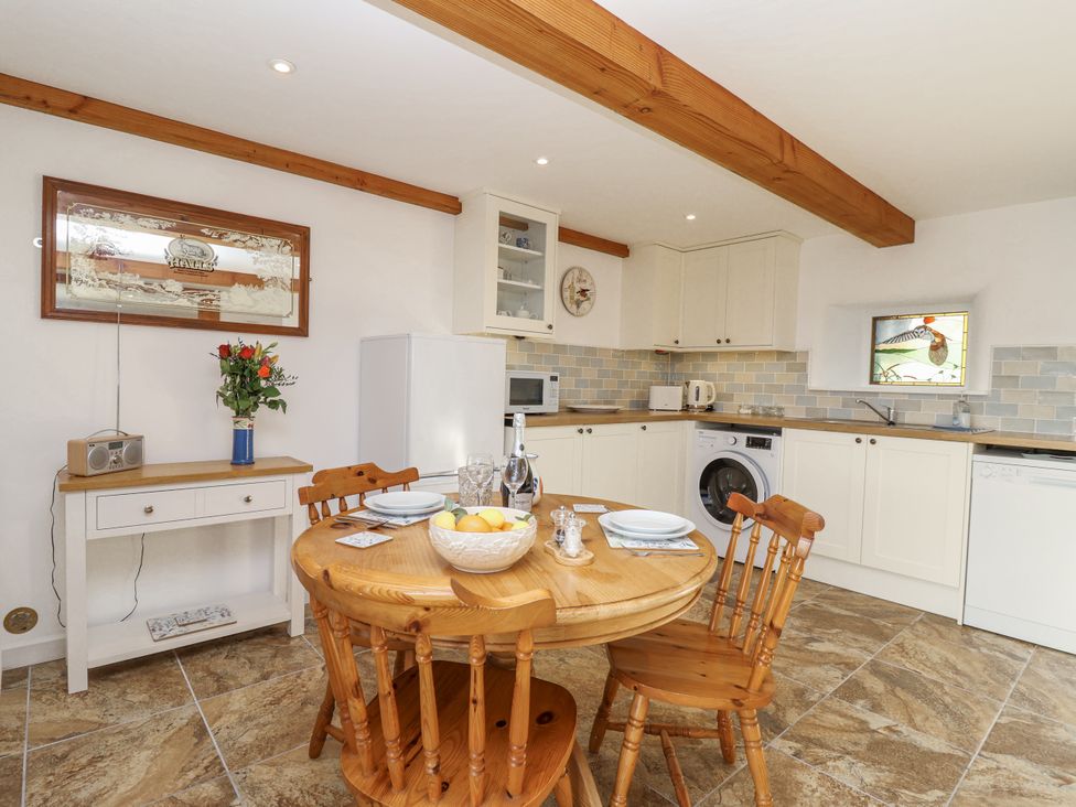 A kitchen with a round table and chairs at Swallow Cottage in Bullhornstone near South Brent