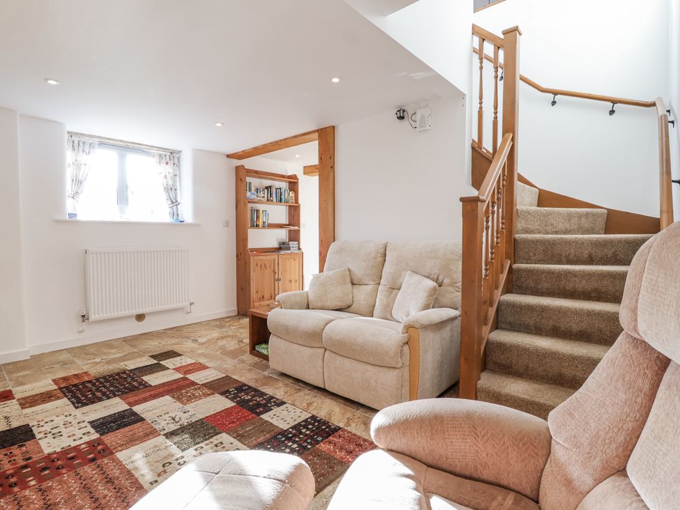 A living room with a sofa and bookshelf at Swallow Cottage Bullhornstone near South Brent