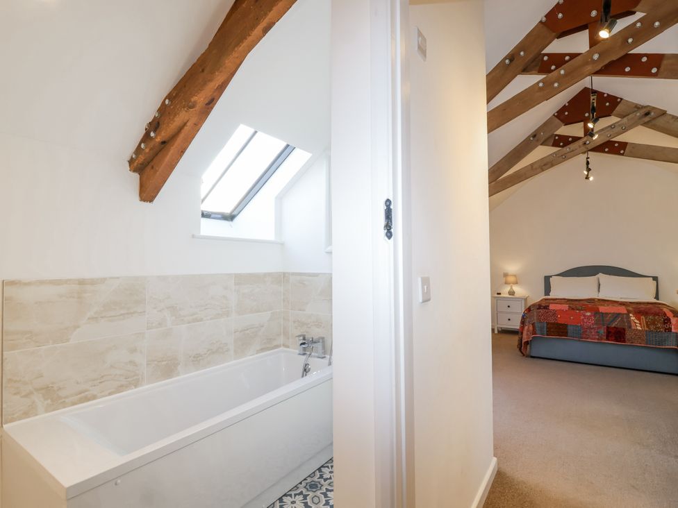 A bathroom with a bathtub and an adjoining bedroom at Swallow Cottage near South Brent