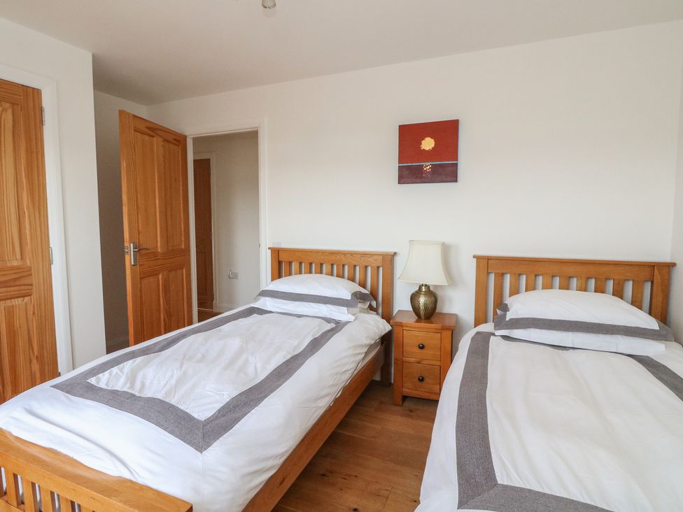 A bedroom with two beds and a bedside table at Lurach House, Port Appin