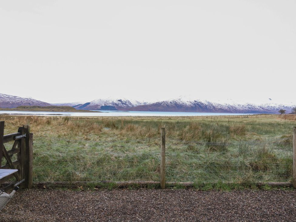 A view of mountains and water from a fence at Lurach House in Port Appin