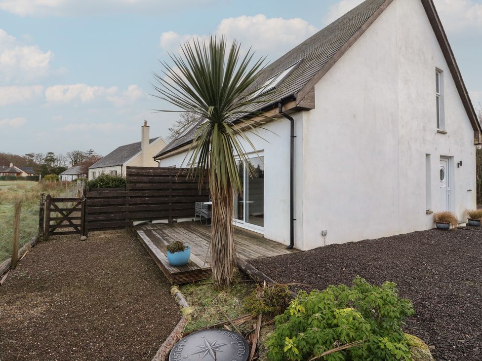 An outdoor area with a palm tree and wooden deck at Sealladh in Appin