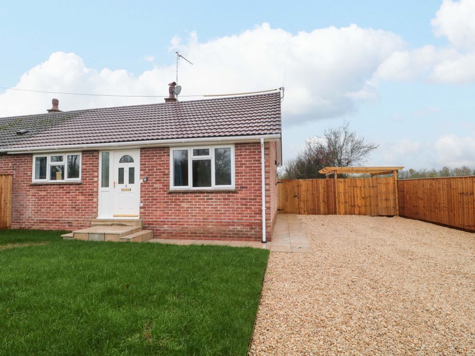 A house with a gravel driveway and grass area at 2 Stroud Bungalows