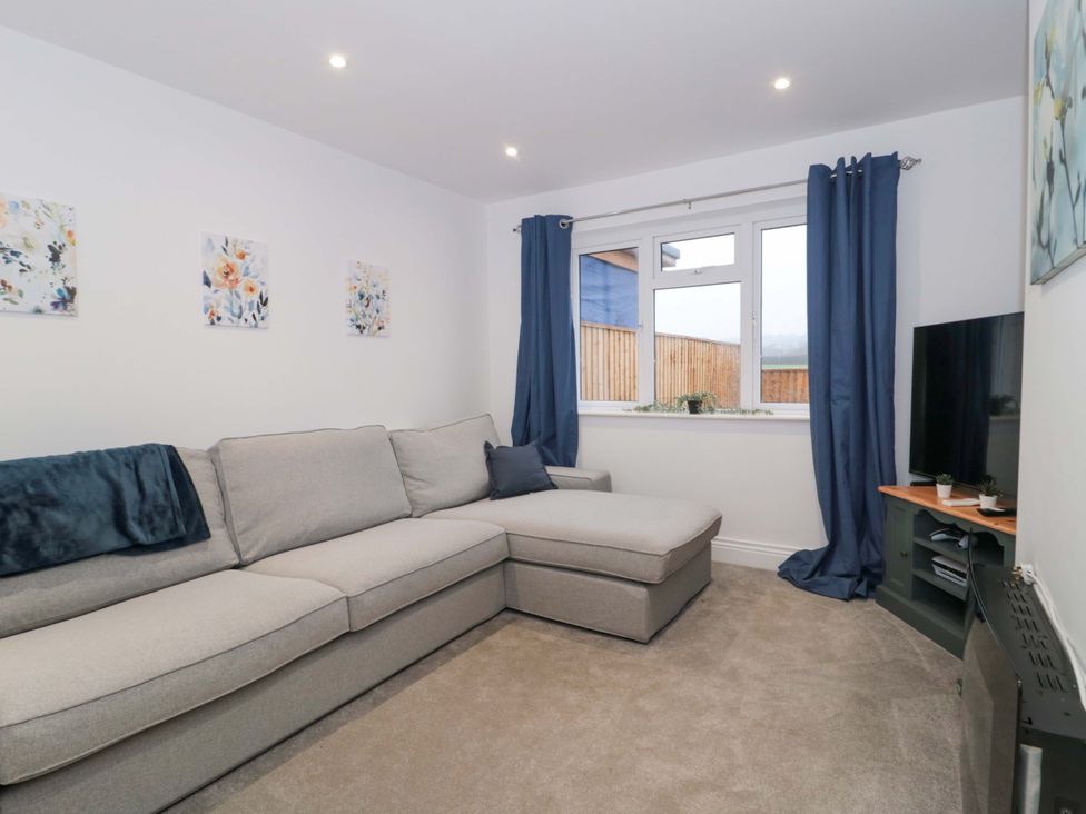 A living room with a sofa and television at 2 Stroud Bungalows