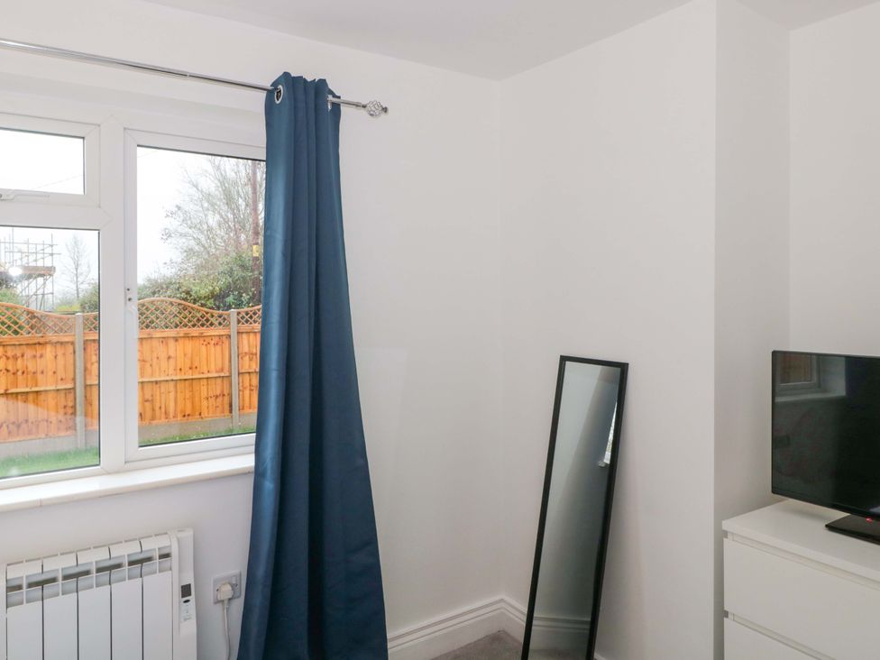 A bedroom with a window and television at 2 Stroud Bungalows