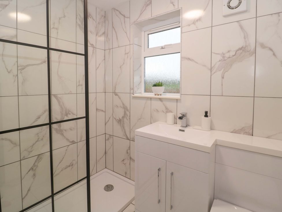 A bathroom with a shower and vanity unit at 2 Stroud Bungalows