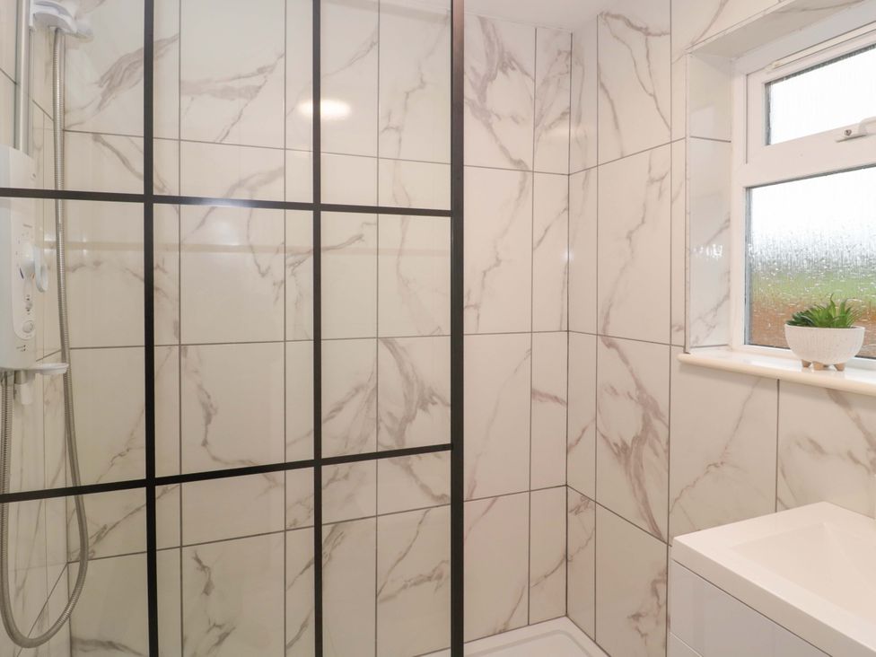 A shower with marble tiles and a window at 2 Stroud Bungalows