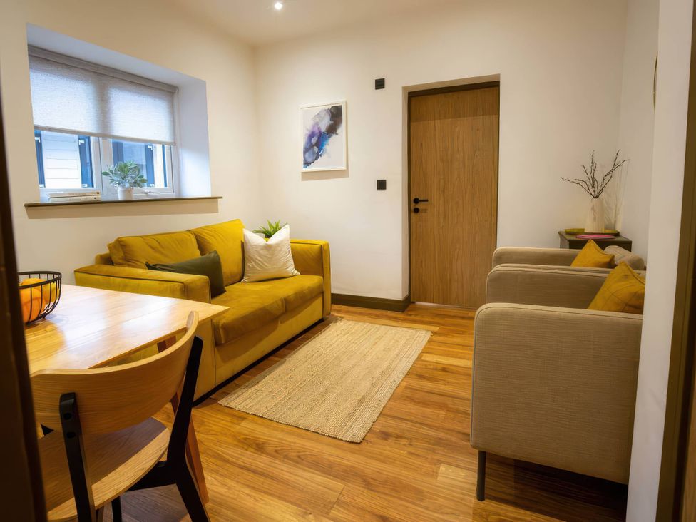 A living room with a sofa and dining table at Aspen Apartment in Llanrwst