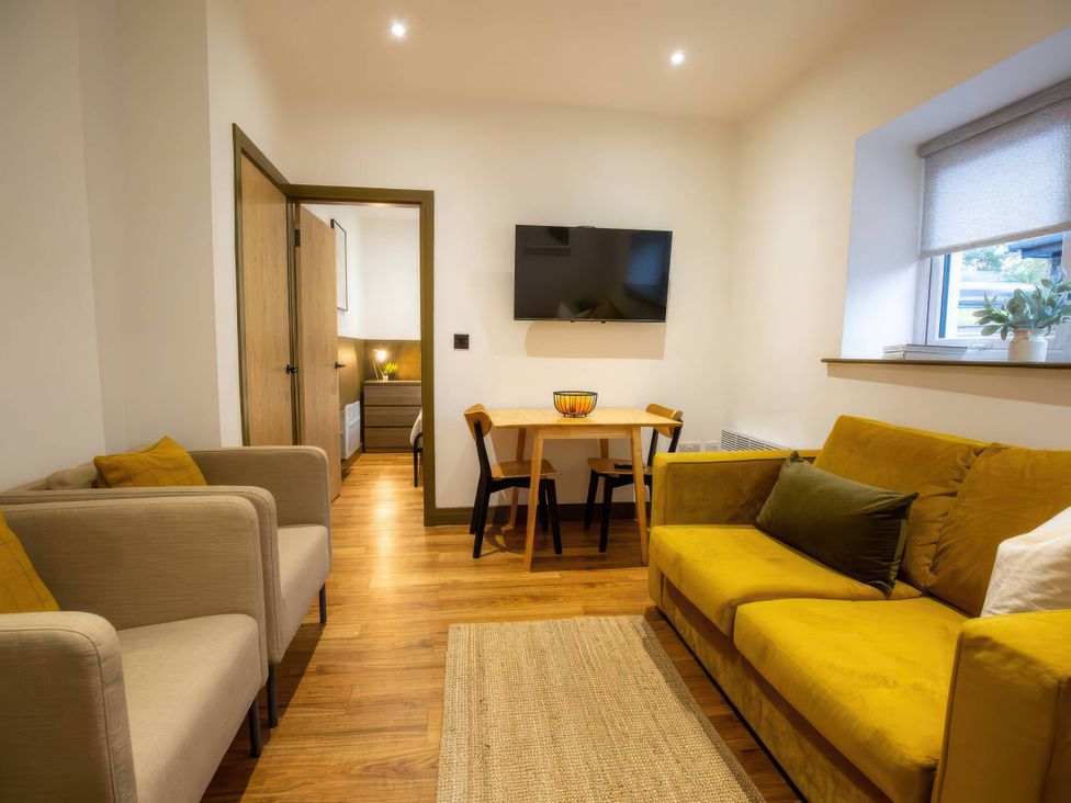 A living room with a dining table and sofa at Aspen Apartment in Llanrwst