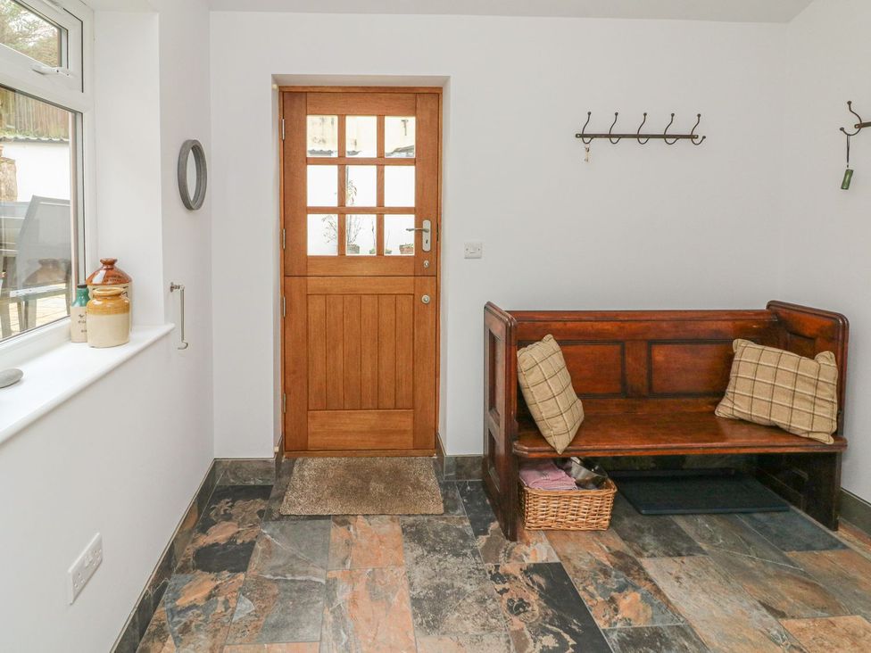 An entrance hall with a wooden bench and door at The Old Workshop 