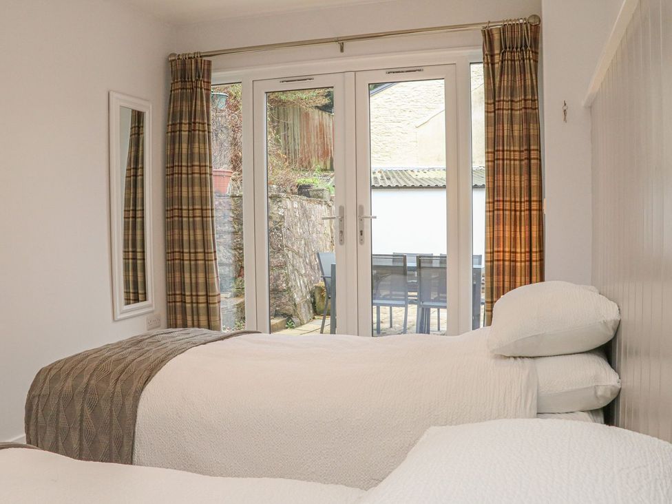 A bedroom with two beds and a door leading to the outside area at The Old Workshop 