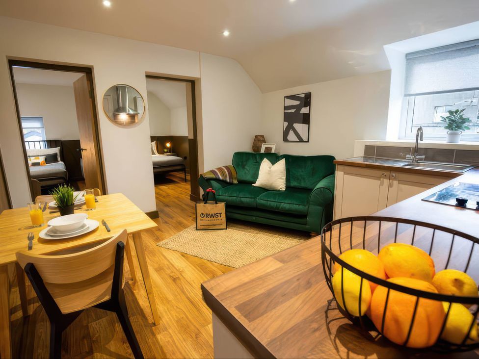 A living room with a sofa and dining table at White Willow Apartment in Llanrwst