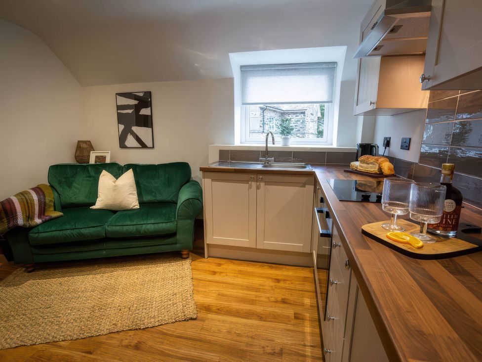 A kitchen with a green sofa and countertop at White Willow Apartment Llanrwst