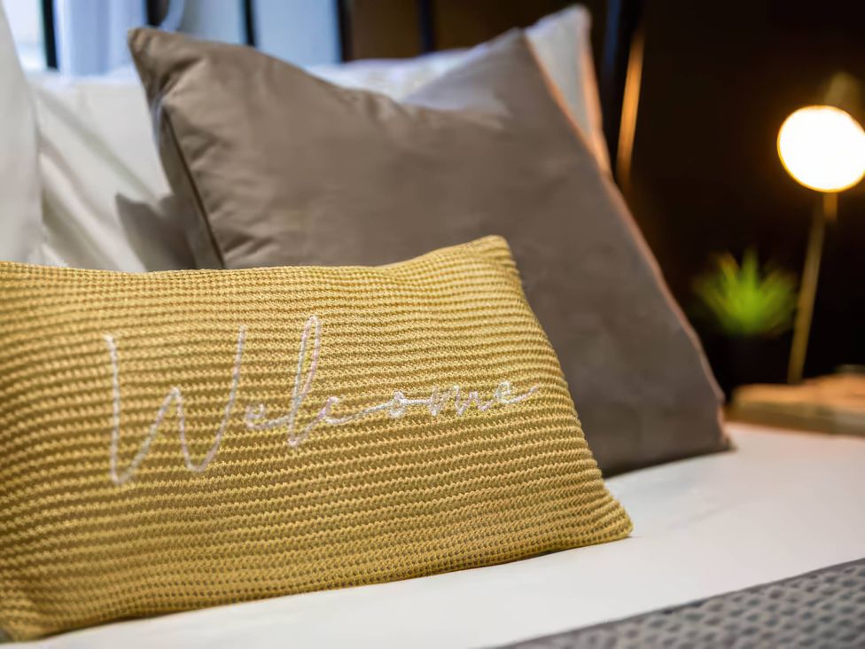 A bed with pillows and a lamp at White Willow Apartment in Llanrwst