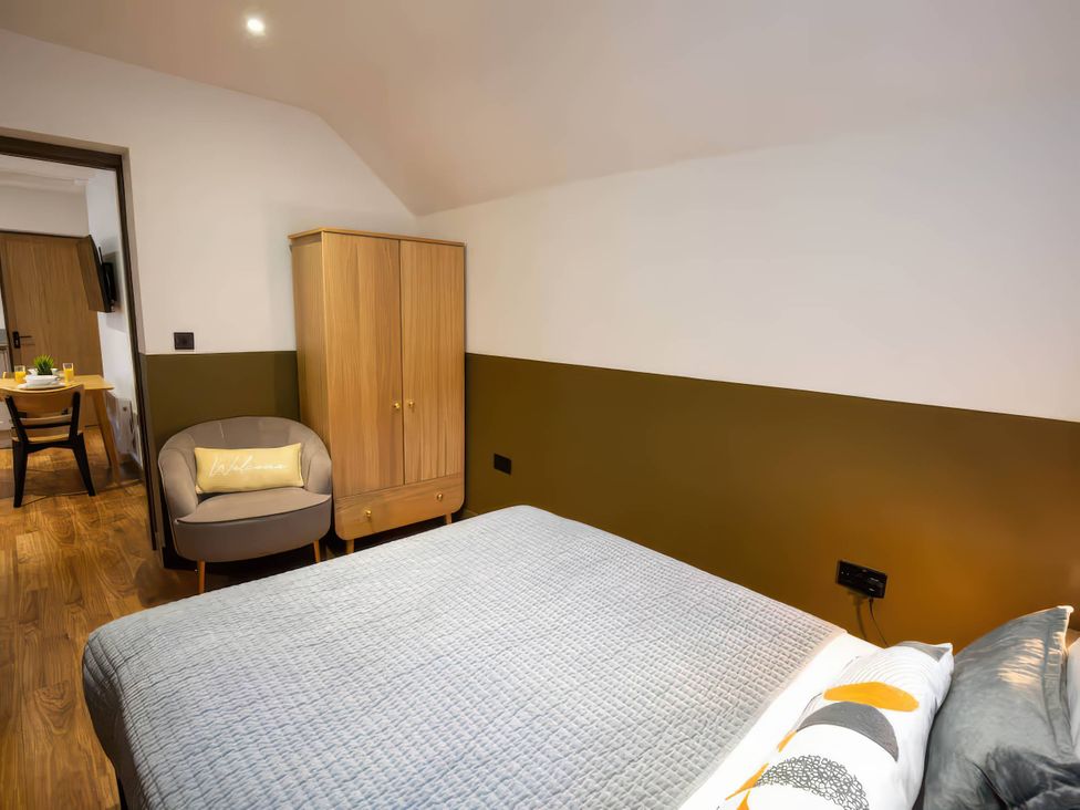 A bedroom with a bed and wardrobe at White Willow Apartment in Llanrwst
