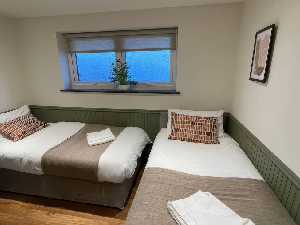 A bedroom with two beds and a window at Ash Cottages, Llanrwst