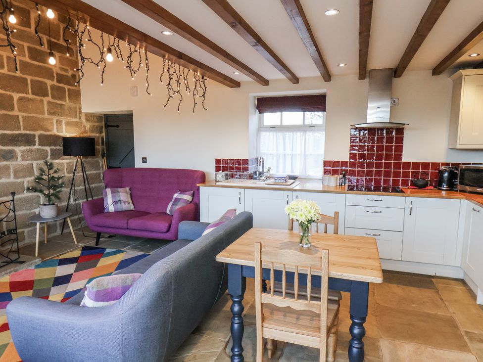 A kitchen with a dining table and sofa at Chestnut Barn Aislaby near Whitby
