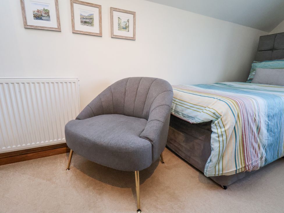 A bedroom with a bed and armchair at Chestnut Barn Aislaby near Whitby