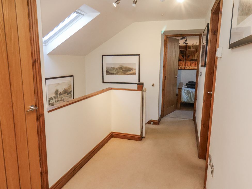 A hallway with paintings on the wall and a door at Chestnut Barn Aislaby near Whitby