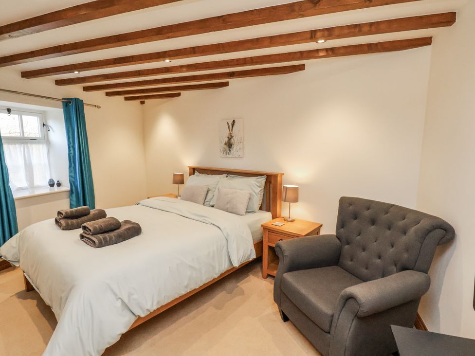 A bedroom with a bed and armchair at Chestnut Barn Aislaby near Whitby