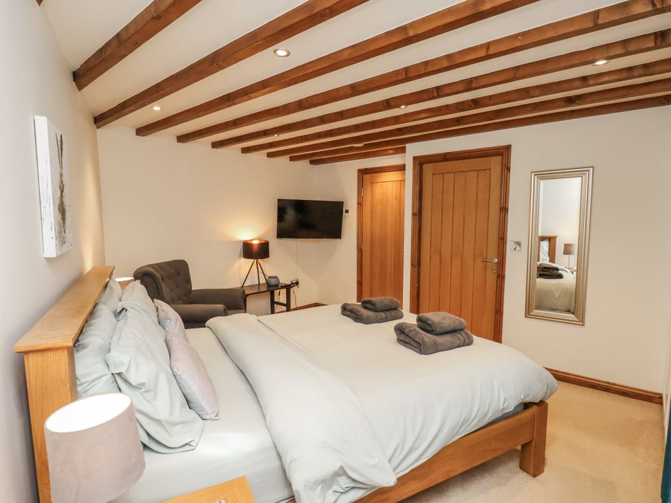 A bedroom with a bed and armchair at Chestnut Barn Aislaby near Whitby
