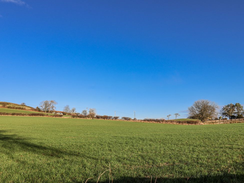 A clear field with trees and a farmhouse at Chestnut Barn Aislaby near Whitby