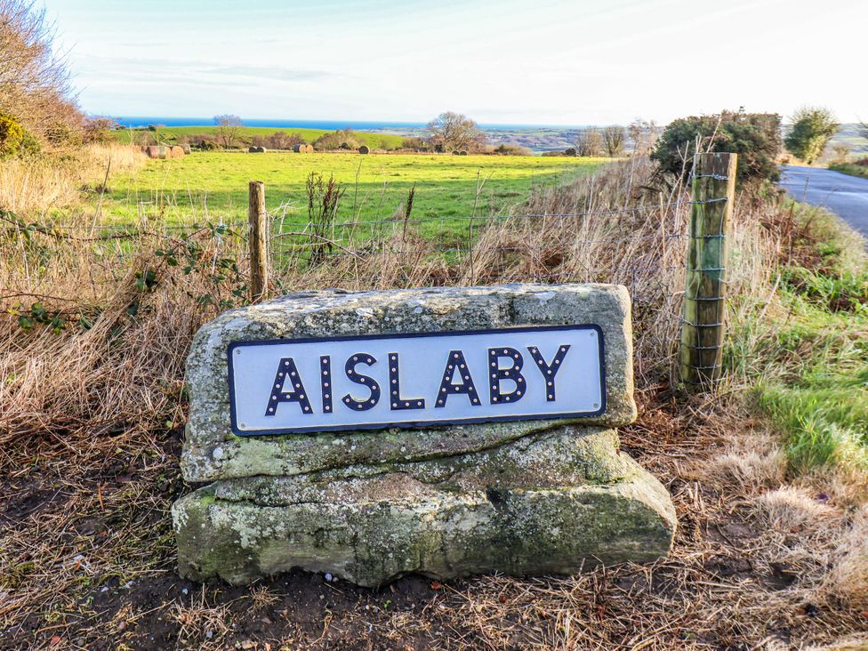 A sign for Aislaby in a field near a road in Aislaby near Whitby