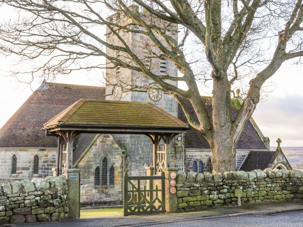 A church with a clock tower and a gate at Chestnut Barn Aislaby near Whitby