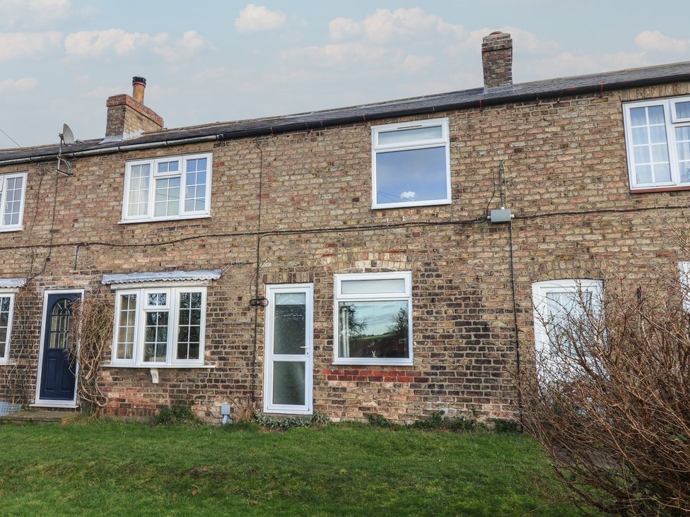Exterior view of a brick house with windows and a door at Daffodil Cottage in York