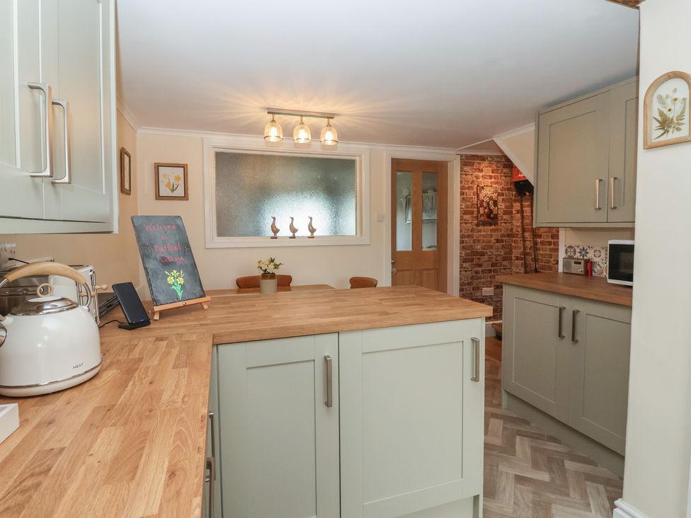 A kitchen with cabinets and a counter at Daffodil Cottage in York