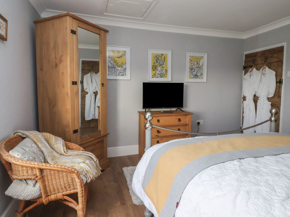 A bedroom with a wardrobe, television and a chair at Daffodil Cottage in York