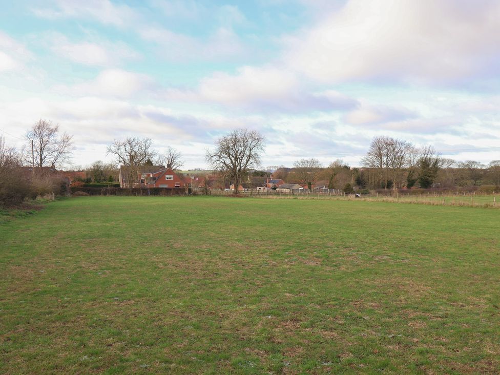 An open field with trees and houses in the background at Daffodil Cottage in York