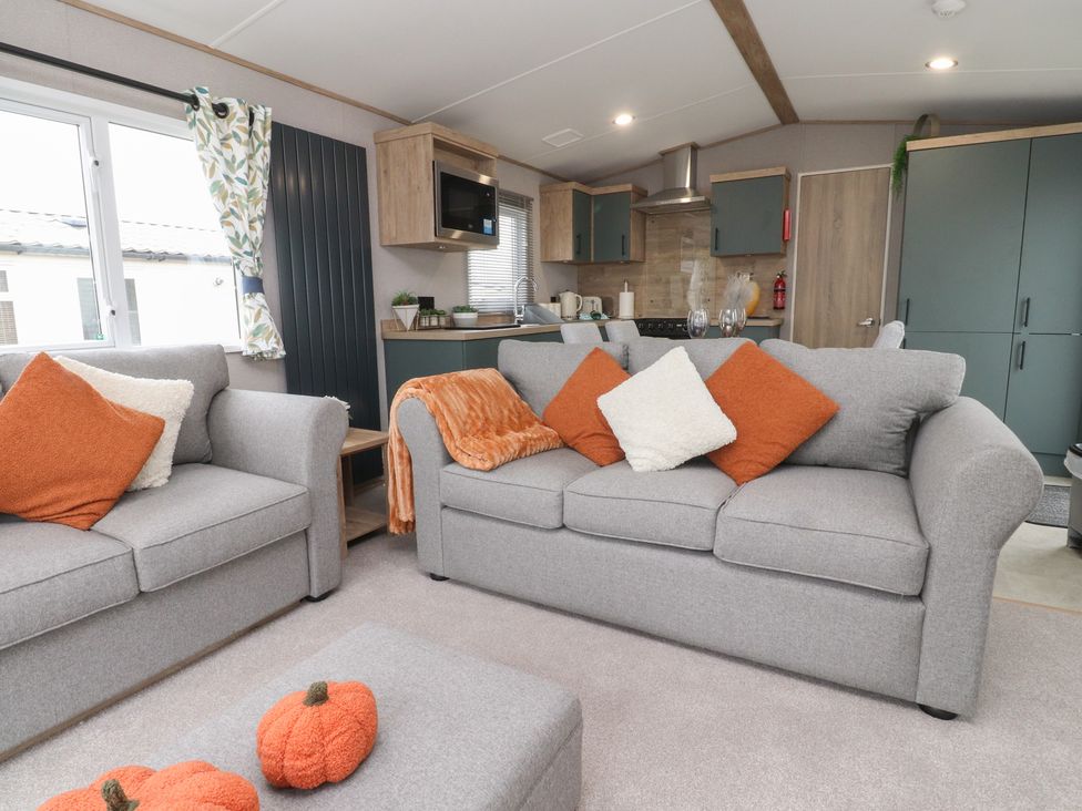 A living room with sofas and kitchen area at The Retreat in Morecambe