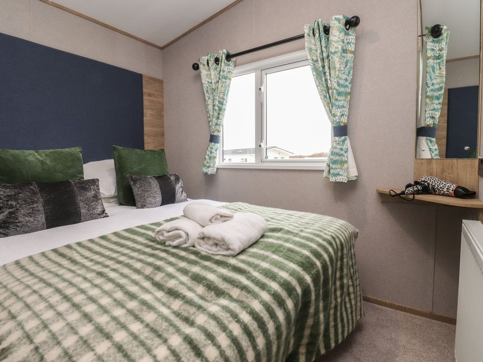 A bedroom with a bed, cushions, and a window at The Retreat in Morecambe