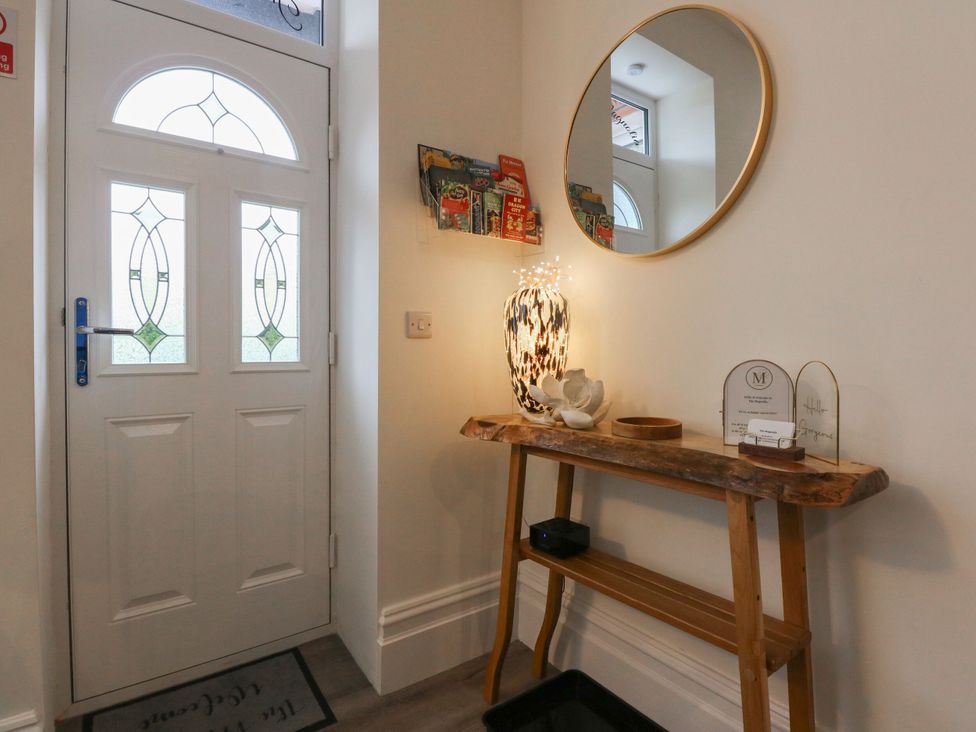 A hallway with a front door and a table with decorative items at The Magnolia in Rhos-On-Sea