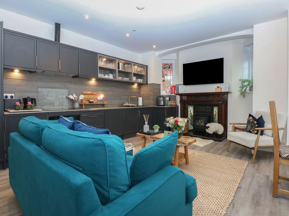 A living room with a sofa and kitchen area at The Magnolia in Rhos-On-Sea