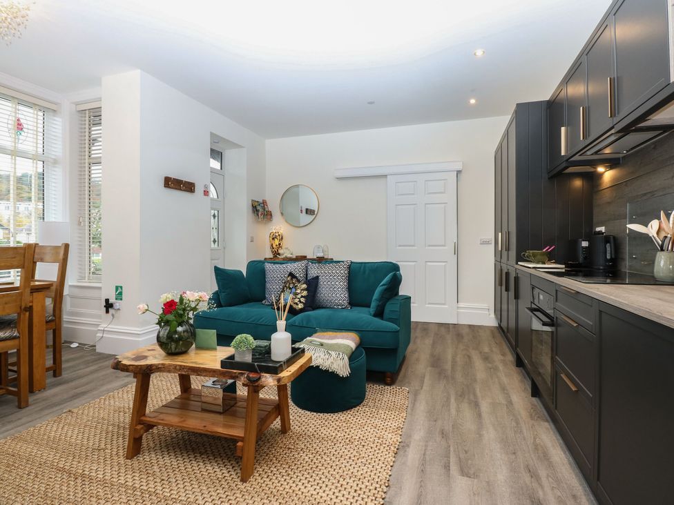 A living room with a sofa and kitchen area at The Magnolia in Rhos-On-Sea