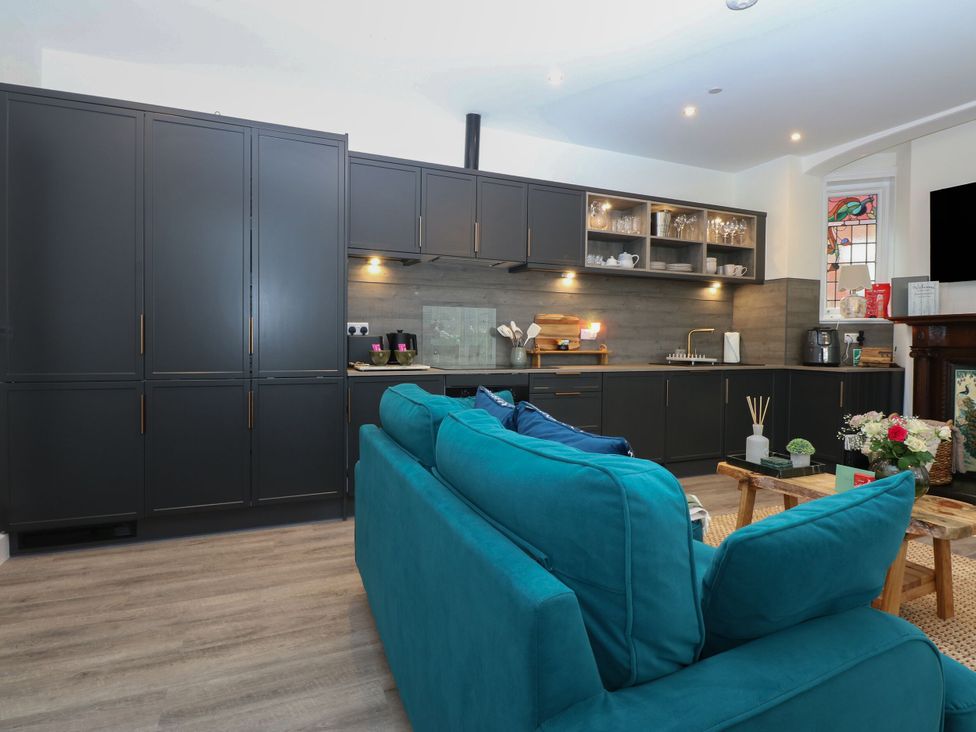 A kitchen with cabinets and a sofa at The Magnolia in Rhos-On-Sea