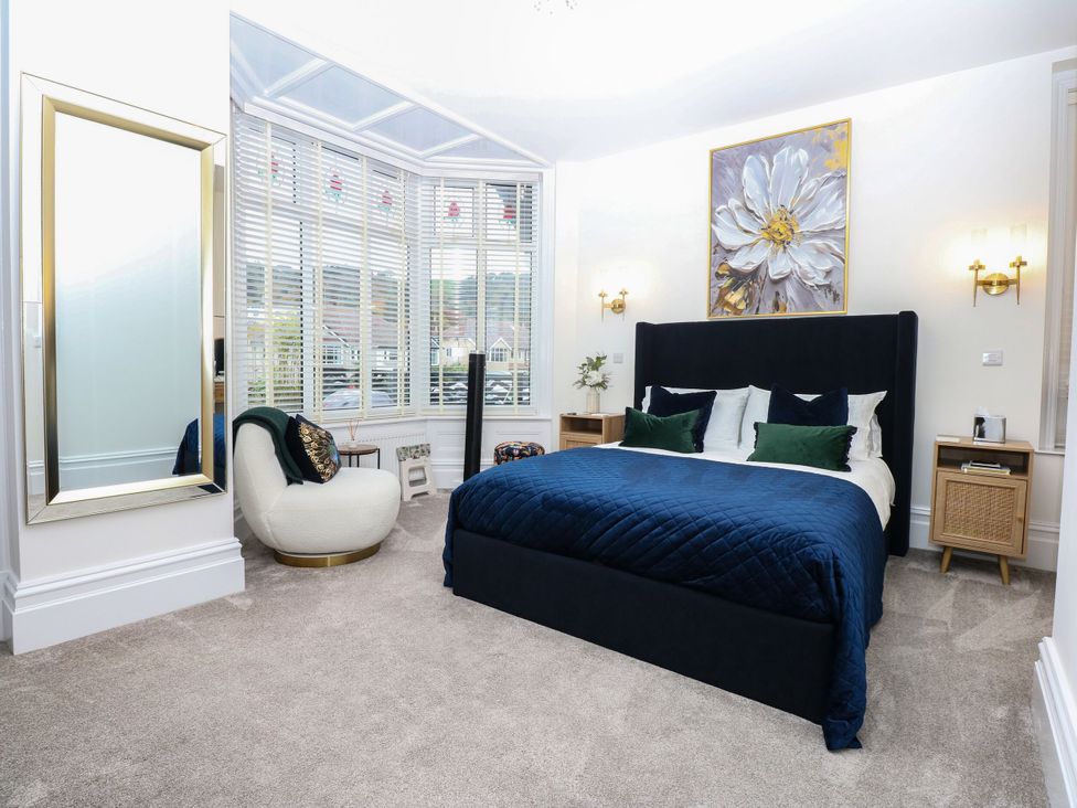 A bedroom with a bed and a chair at The Magnolia in Rhos-On-Sea